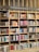 A bookshelf filled with a variety of books categorized under Ibero-American literature. The shelves are organized with books displayed upright and stacked, showcasing colorful covers and titles. The structure is wooden with sections divided by horizontal and vertical beams.