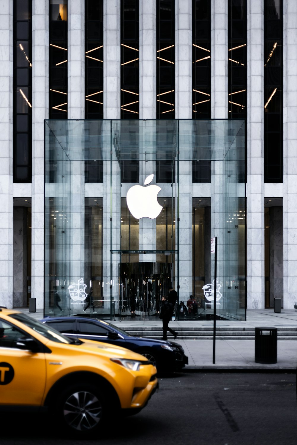 a yellow taxi cab driving past an apple store