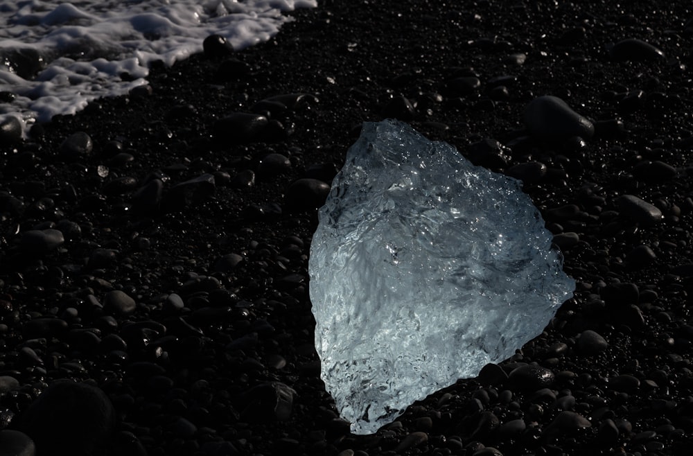 a rock on a beach with a wave coming in