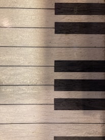 A close-up view of a section of piano keys with a focus on the texture of the material. The keys alternate between white and black, creating a classic and elegant appearance.