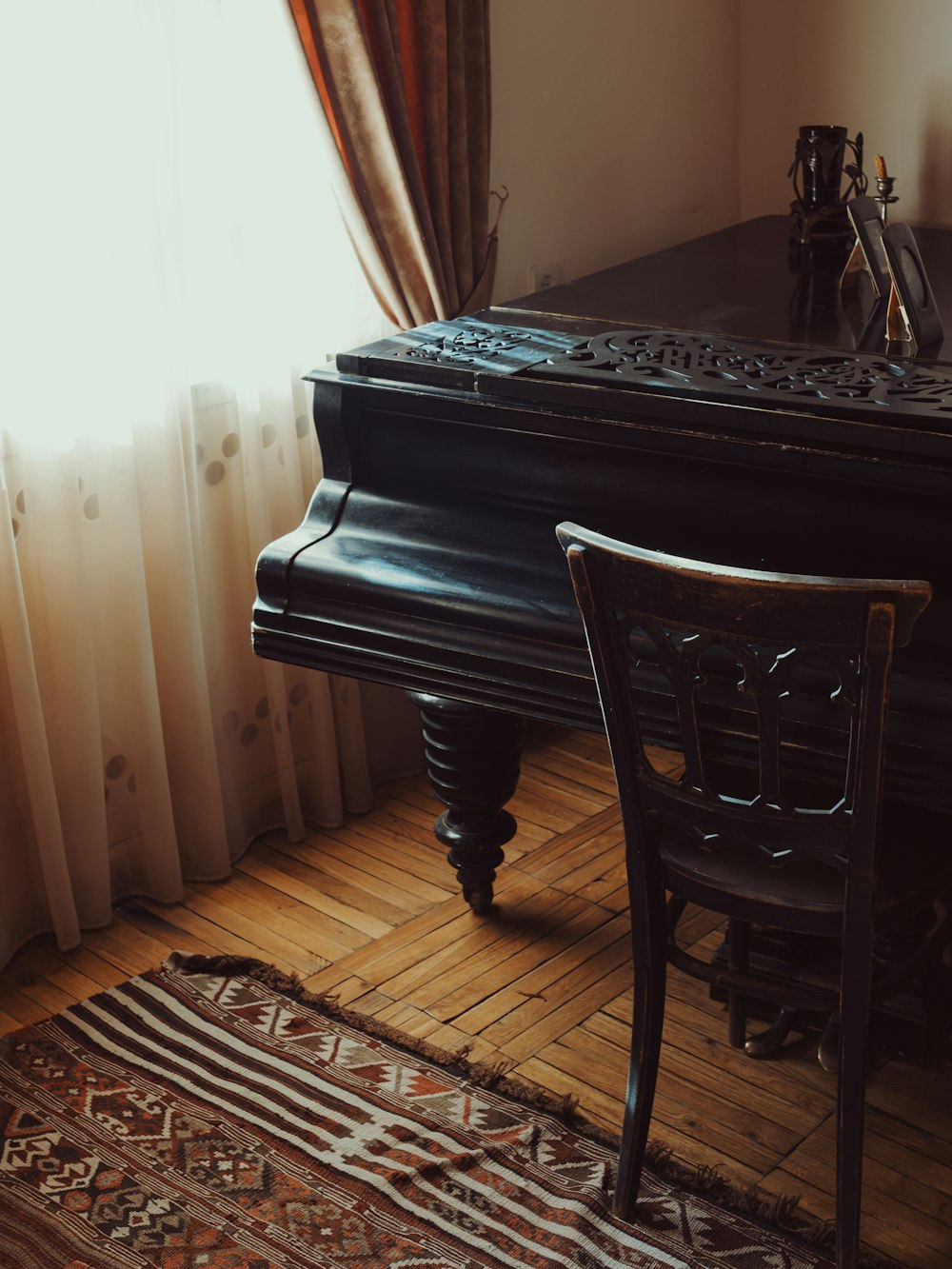 a piano sitting on top of a wooden floor next to a window