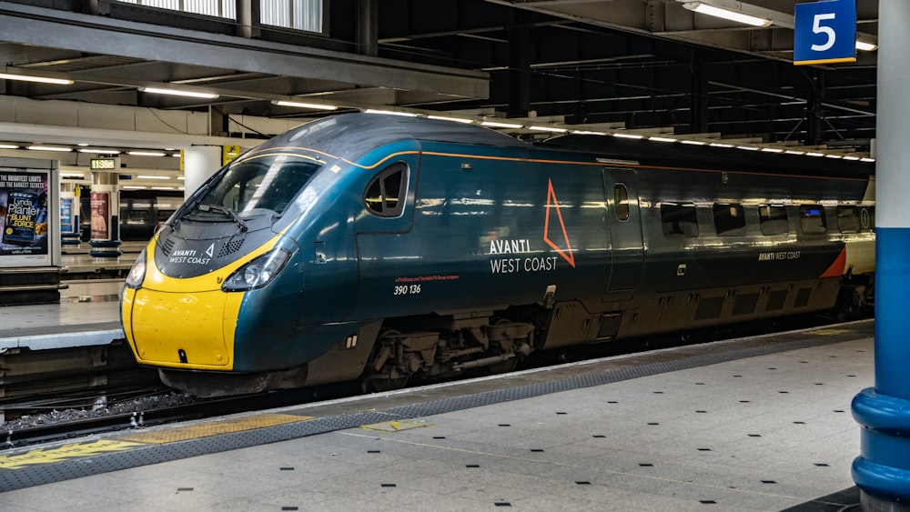 a blue and yellow train pulling into a train station