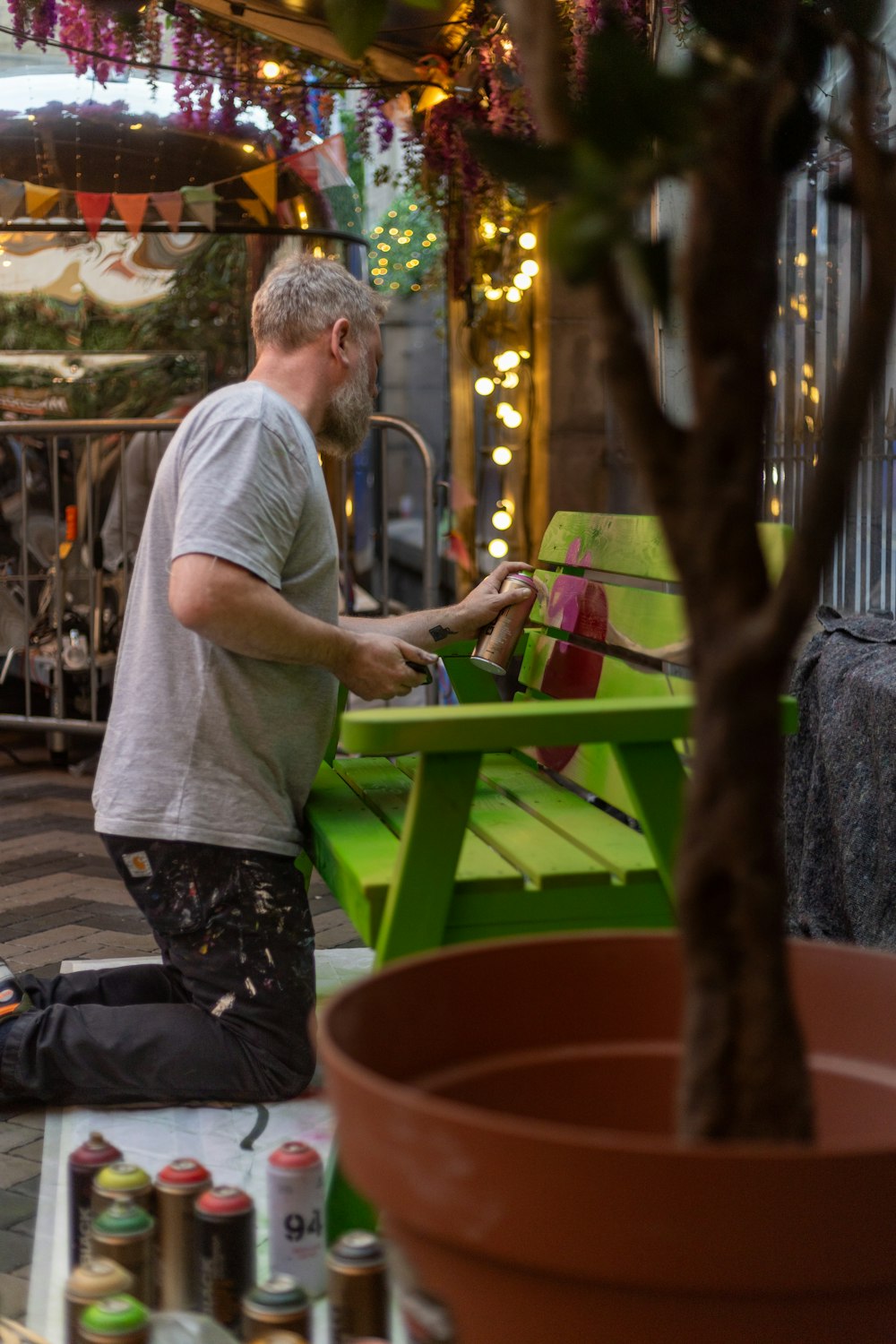 a man sitting on a green bench next to a tree