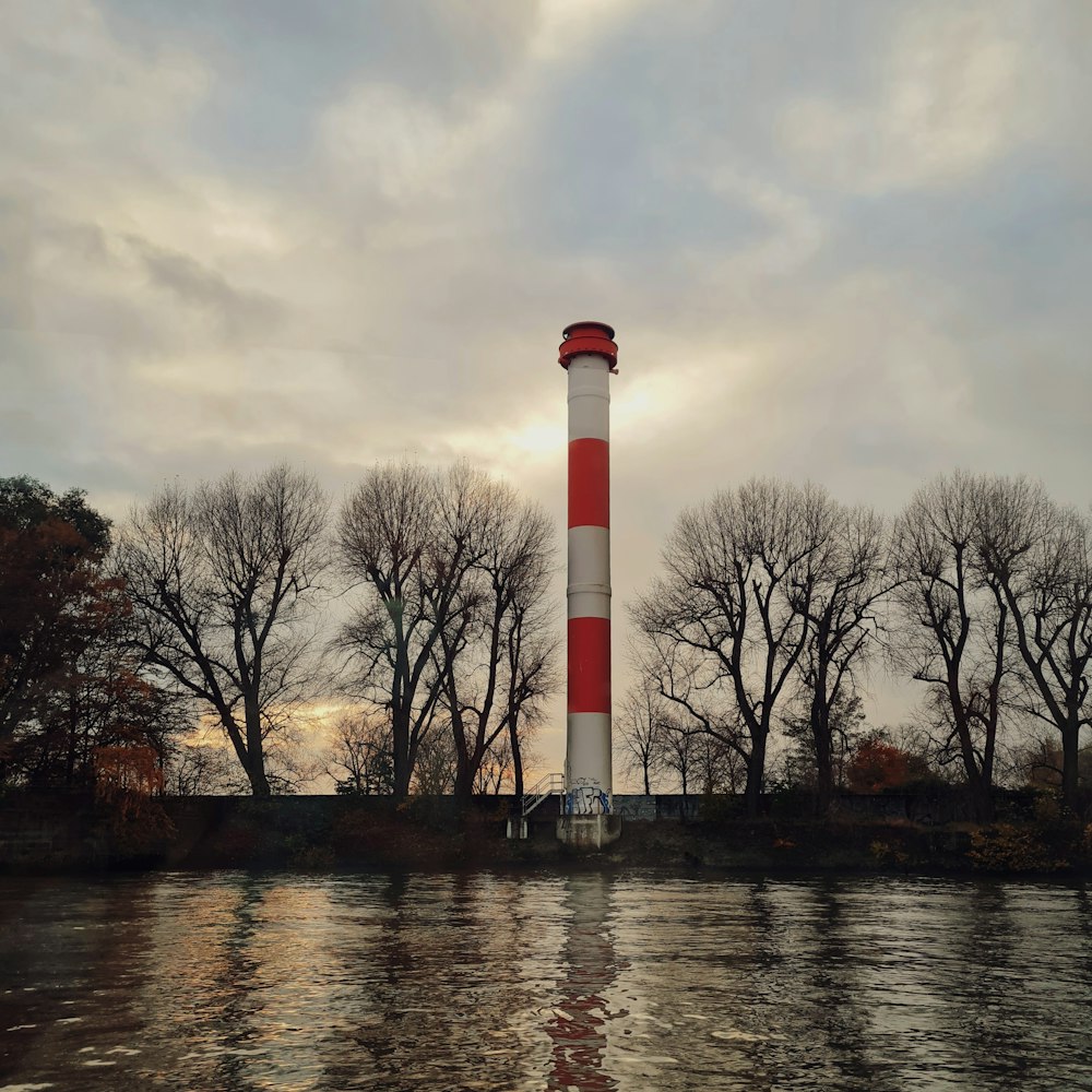 a red and white light house surrounded by trees