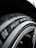 A close-up view of a car tire with the text 'Pilot Sport' clearly visible on the sidewall. The tire texture and tread details are prominent, set against a dark background that showcases the metallic sheen of the rim.