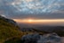 the sun is setting over the mountains and rocks