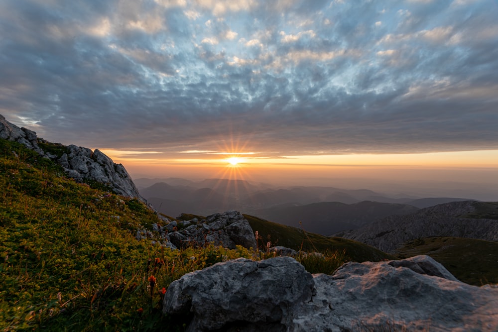 the sun is setting over the mountains and rocks