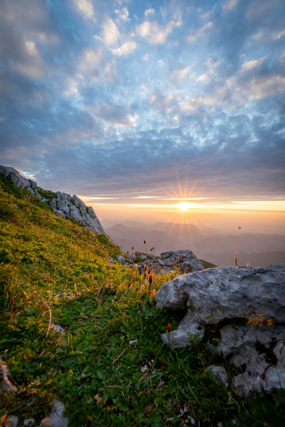 the sun is setting over a grassy hill