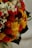 A vibrant floral arrangement featuring a mix of colorful dried flowers, including bright yellow and red blooms, small white and pink blossoms, and some green foliage. The textures vary from soft petals to spiky and fuzzy elements, creating a rich visual tapestry.
