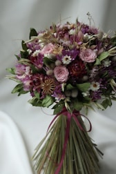 A soft mauve ribbon tied around a finished bouquet with natural greenery.