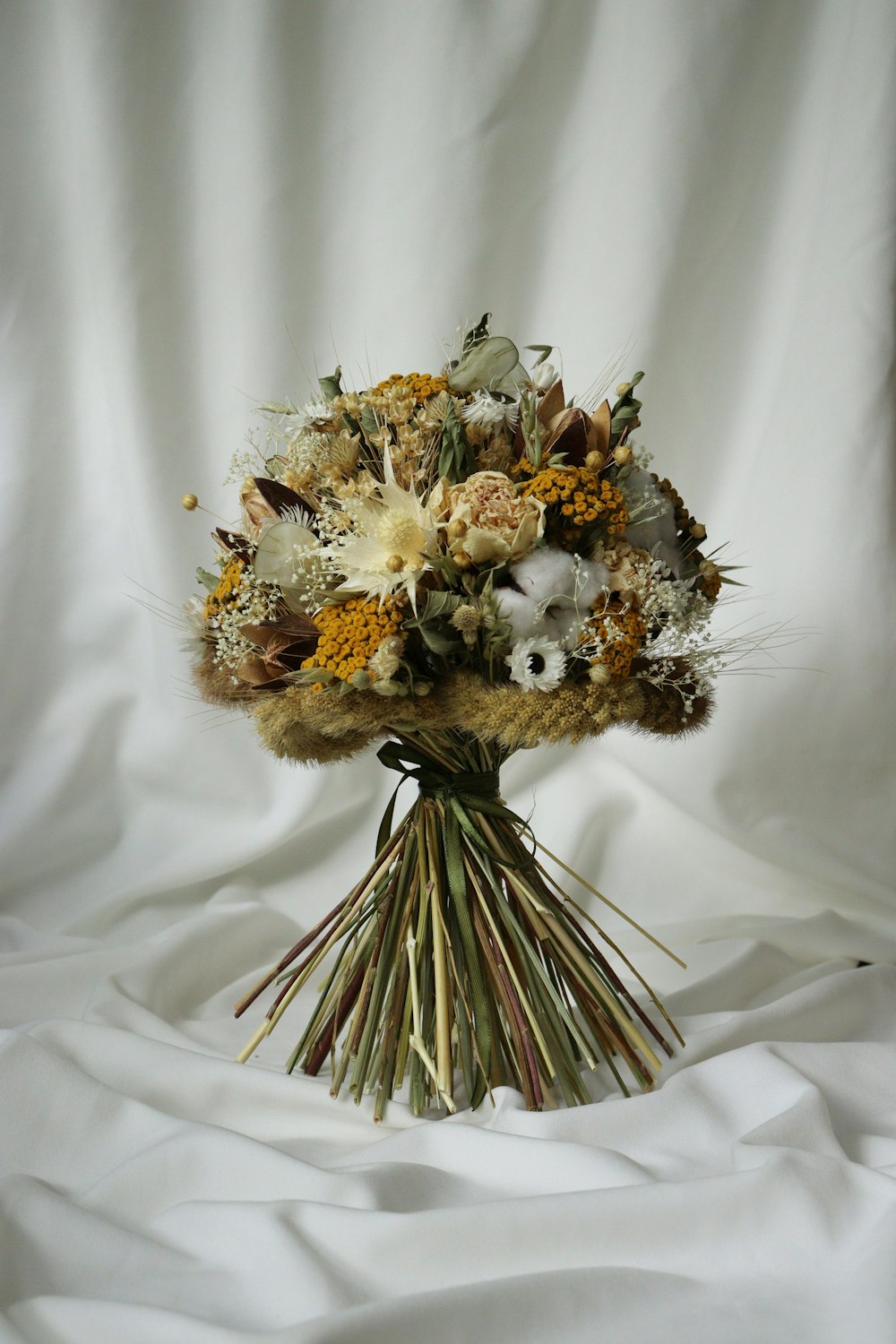 a bouquet of flowers sitting on top of a white sheet