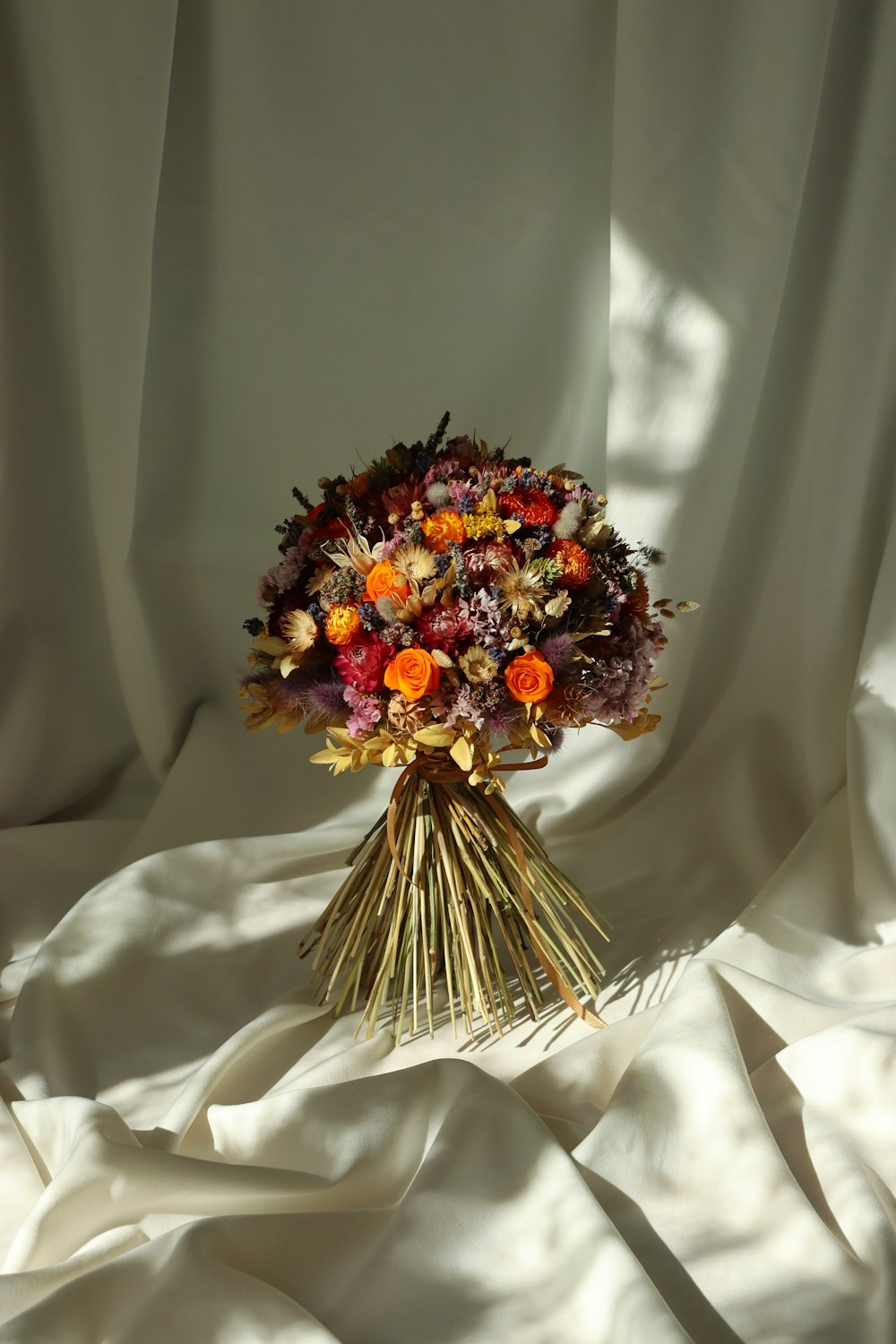 a bouquet of flowers sitting on top of a white sheet