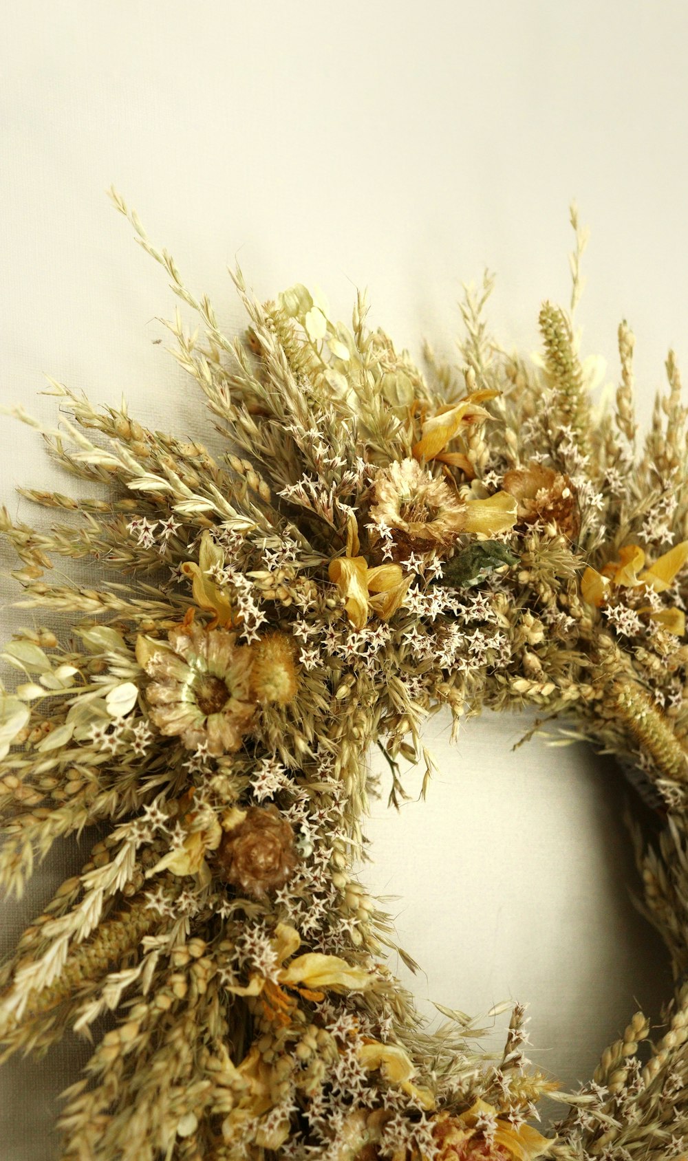a dried wreath with dried flowers on a white wall