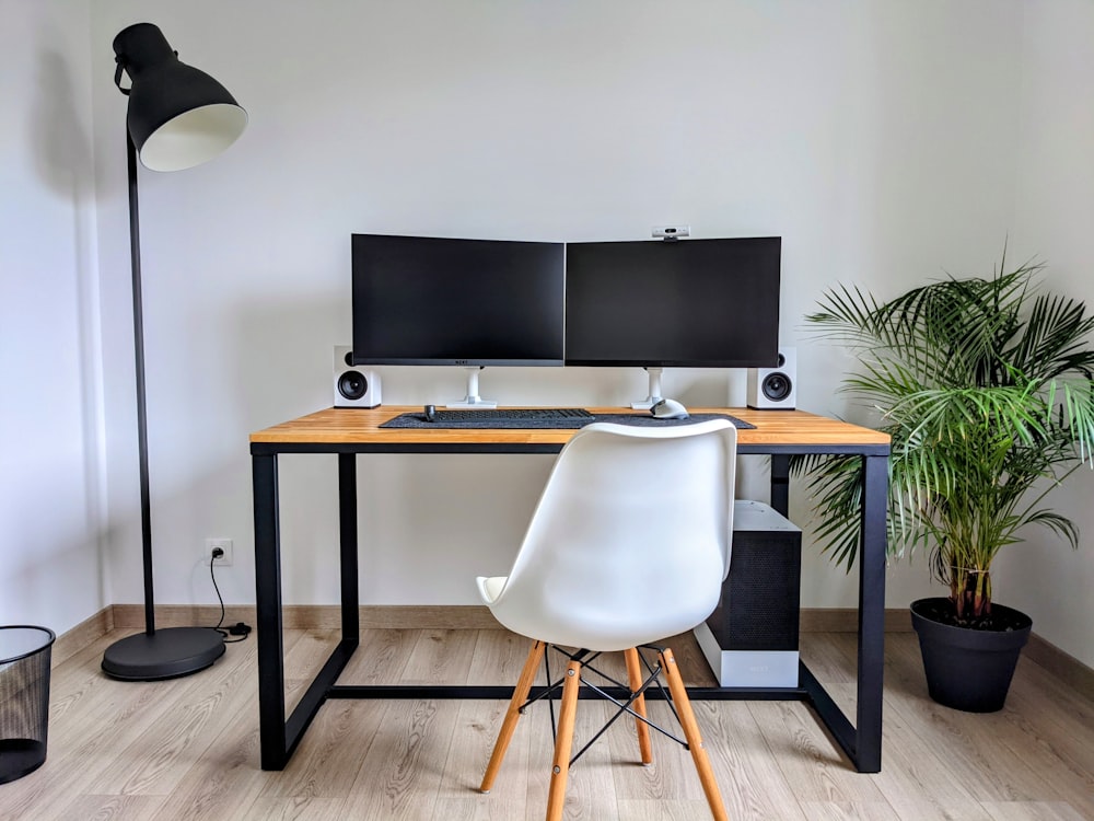 a desk with two computer monitors and a chair