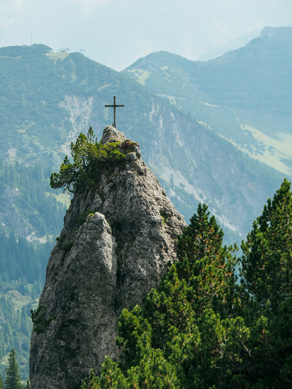 uma cruz no topo de uma rocha nas montanhas