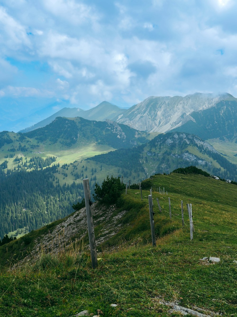 a grassy hill with a fence and mountains in the background