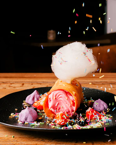 A colorful dessert stand showcasing freshly made funnel cakes dusted with powdered sugar and berries.
