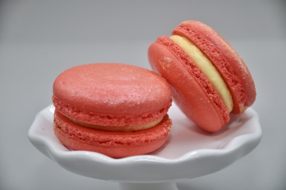 a couple of pink macaroons sitting on top of a white plate