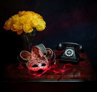 A bright bouquet of fresh flowers resting beside a vintage telephone on a wooden desk.