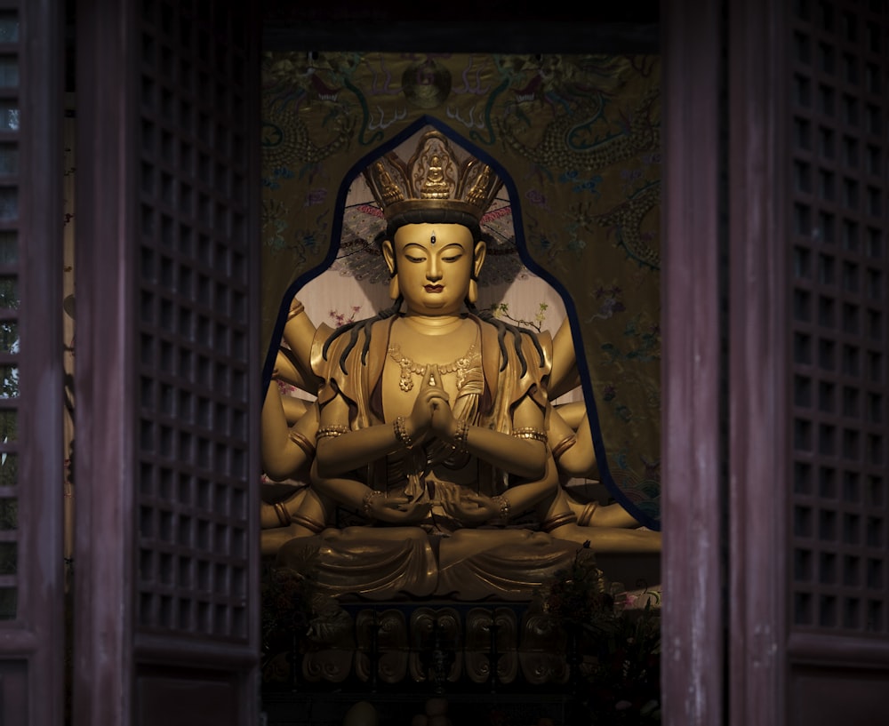 a golden buddha statue sitting in front of a window