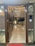 An intricately decorated entryway with a garland of marigold and yellow flowers hanging above a wooden door. The inside view reveals a well-lit interior with glossy marble flooring, modern ceiling designs, and contemporary furniture. Decorative items and soft lighting add to the opulent ambiance.