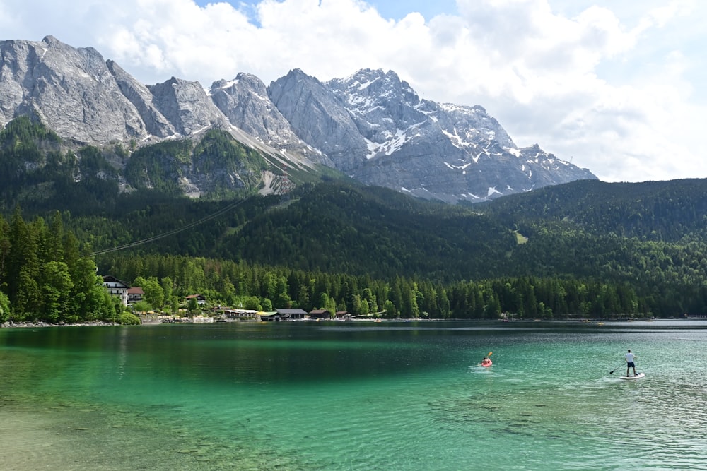 a person on a surfboard in a lake with mountains in the background