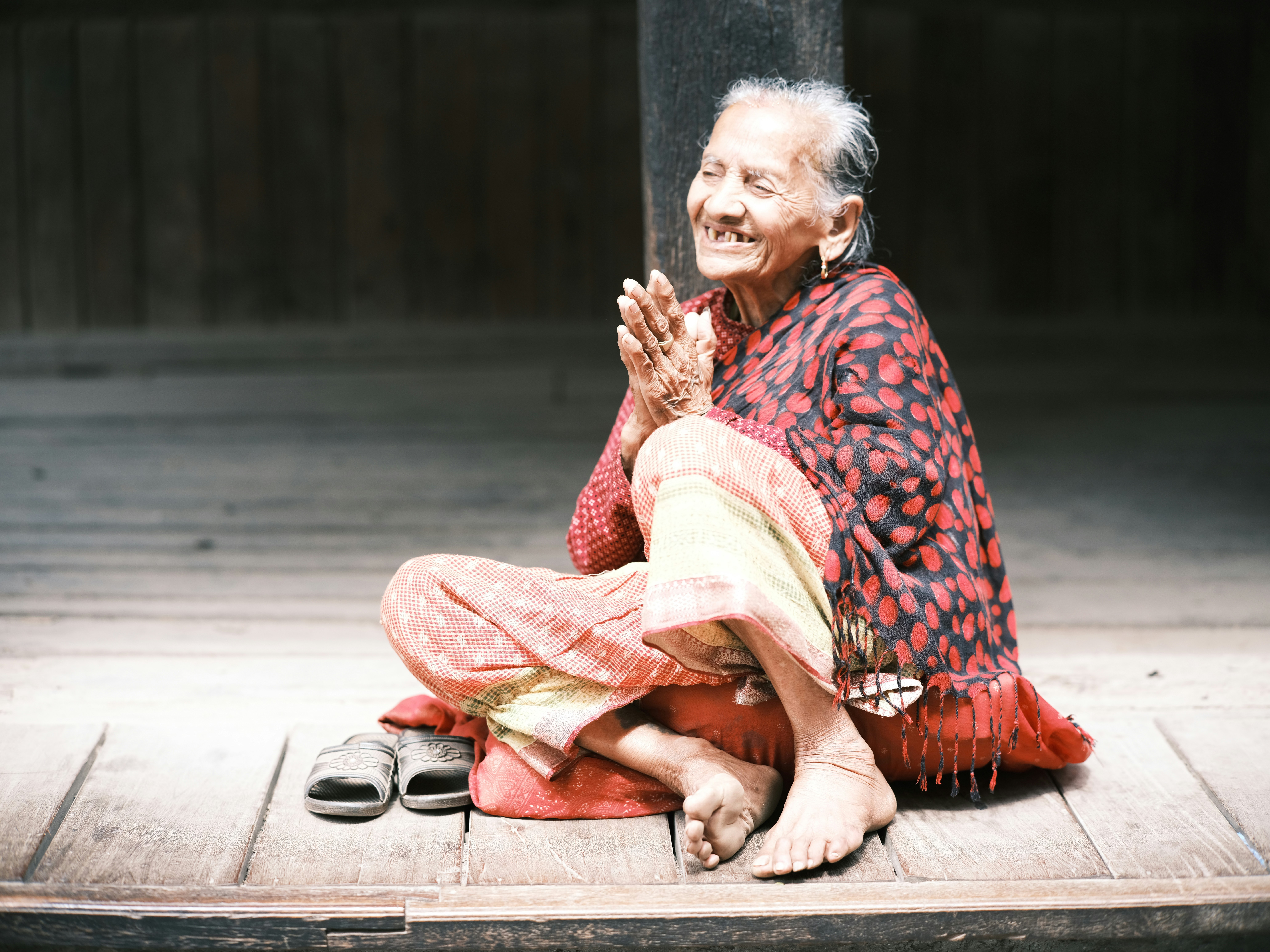 a woman sitting on a wooden floor with her hands together