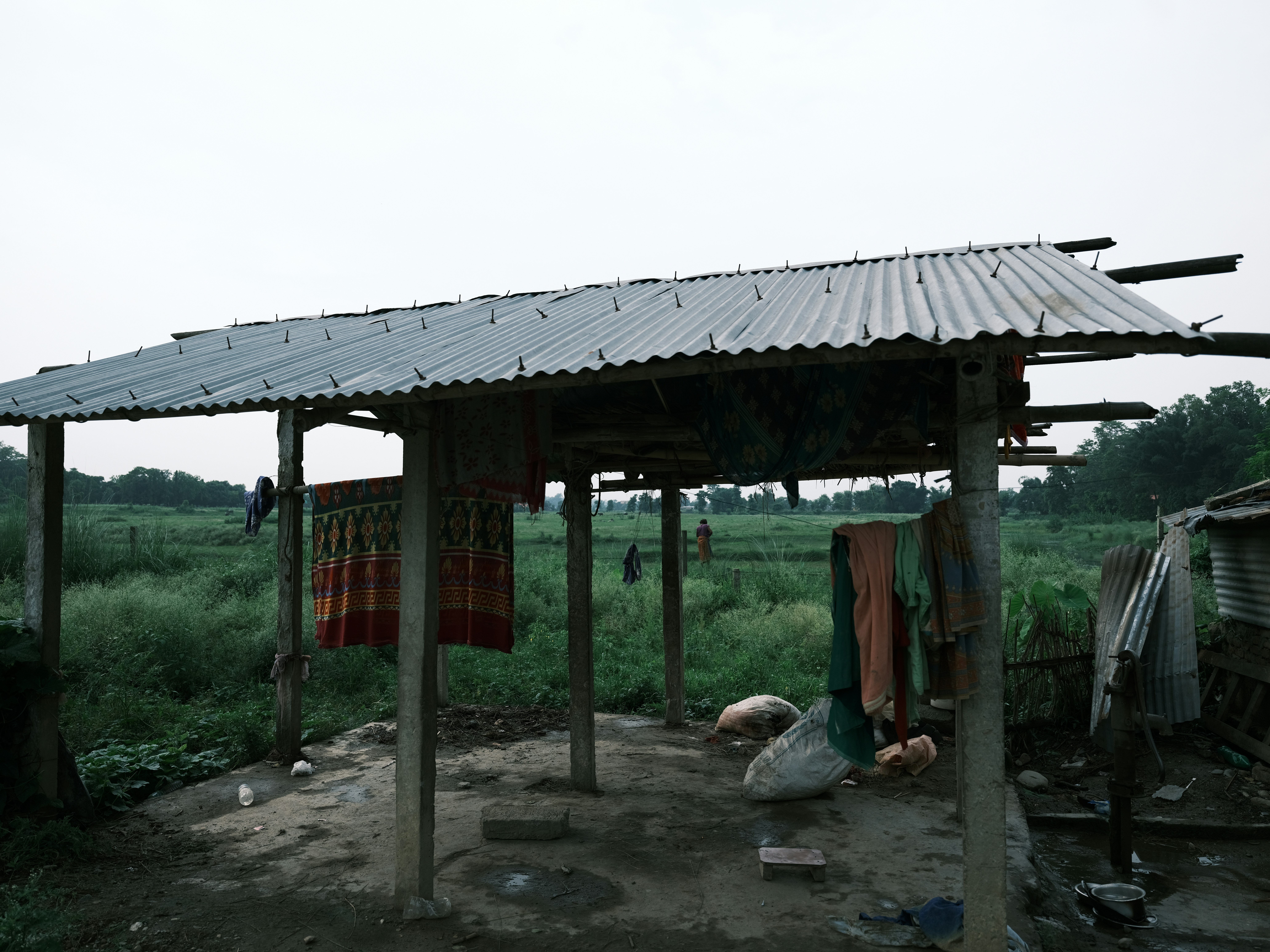 a wooden shelter with a metal roof in the middle of a field