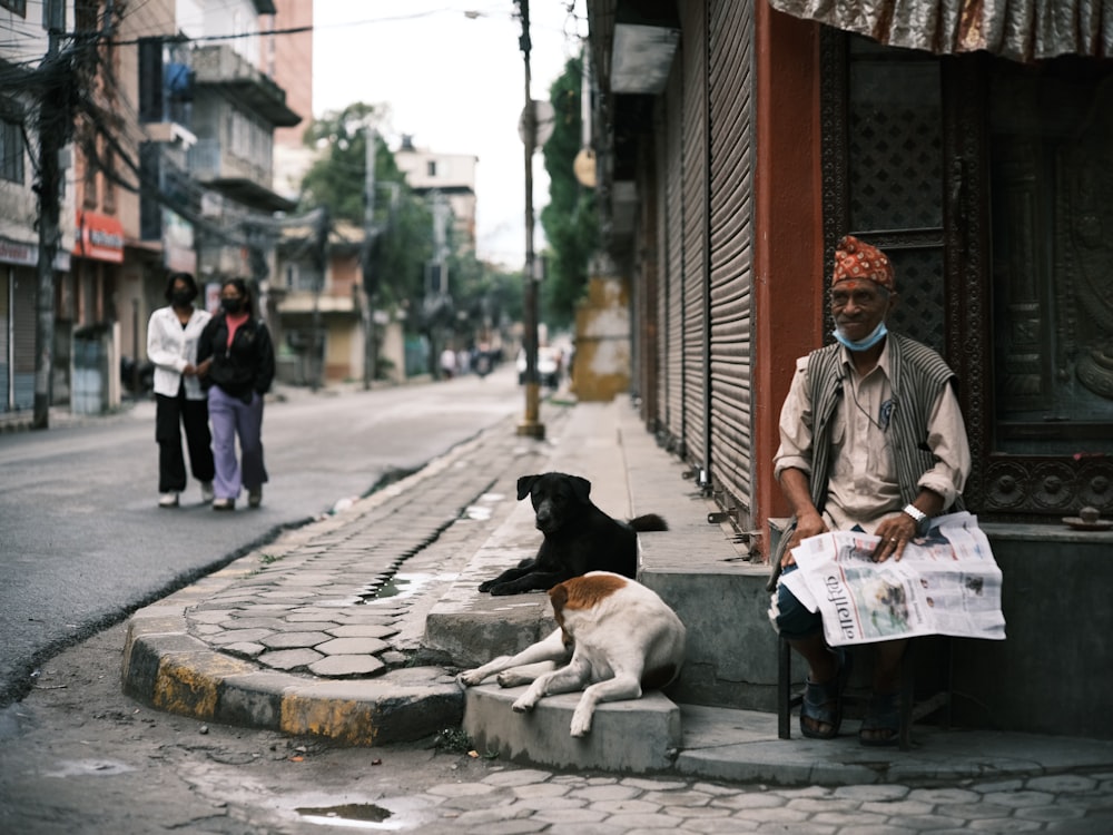 a man sitting next to a dog on a sidewalk