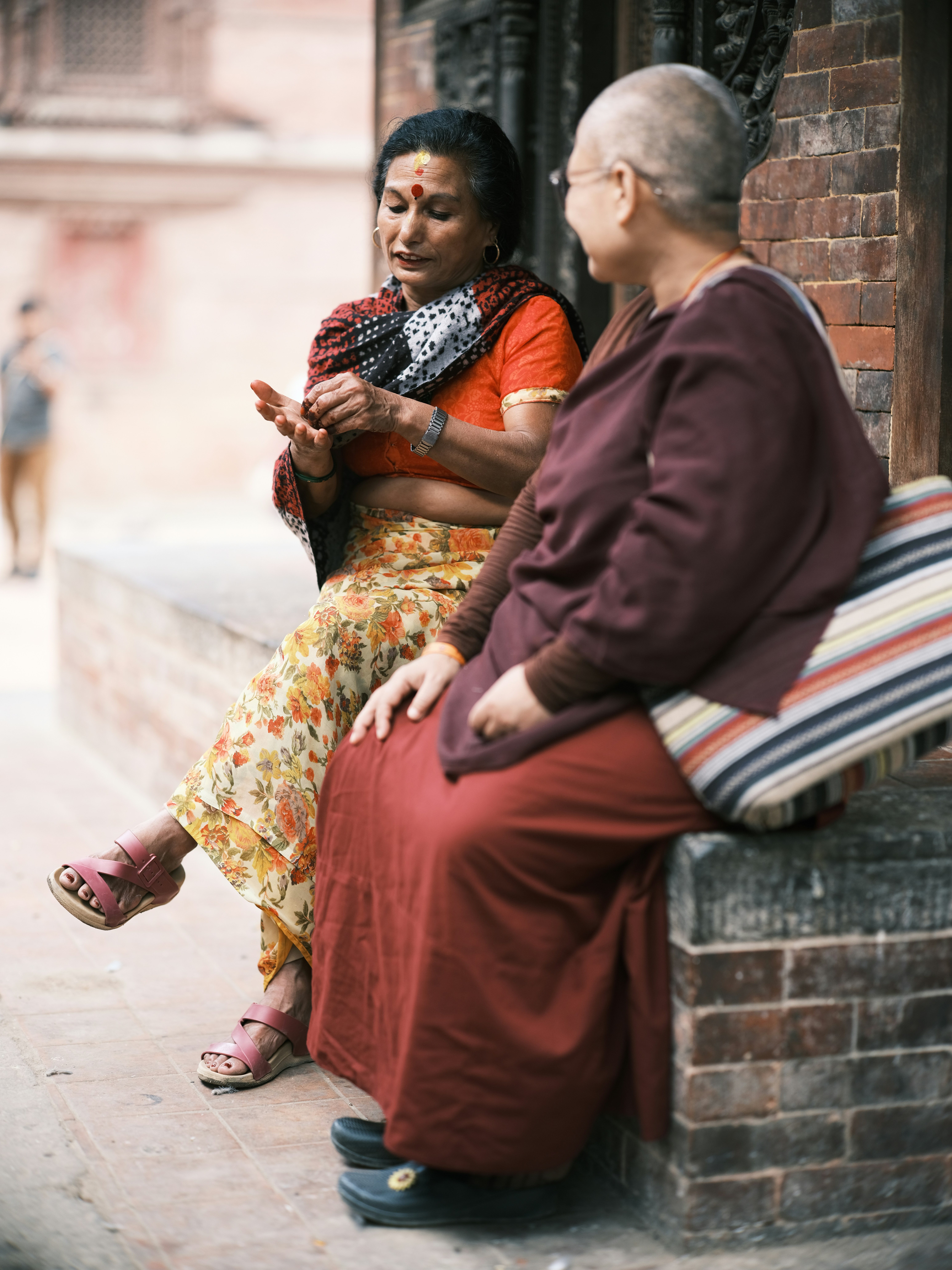 Two women sitting on a bench in front of a building