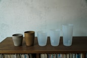 A row of colorful stainless steel cups lined up on a wooden table.