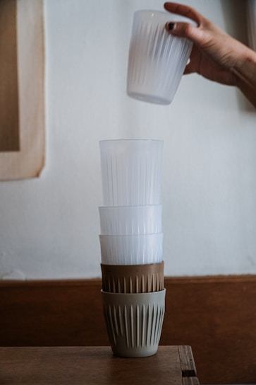 Close-up of sturdy plastic cups stacked neatly on a wooden table in a bright workshop.