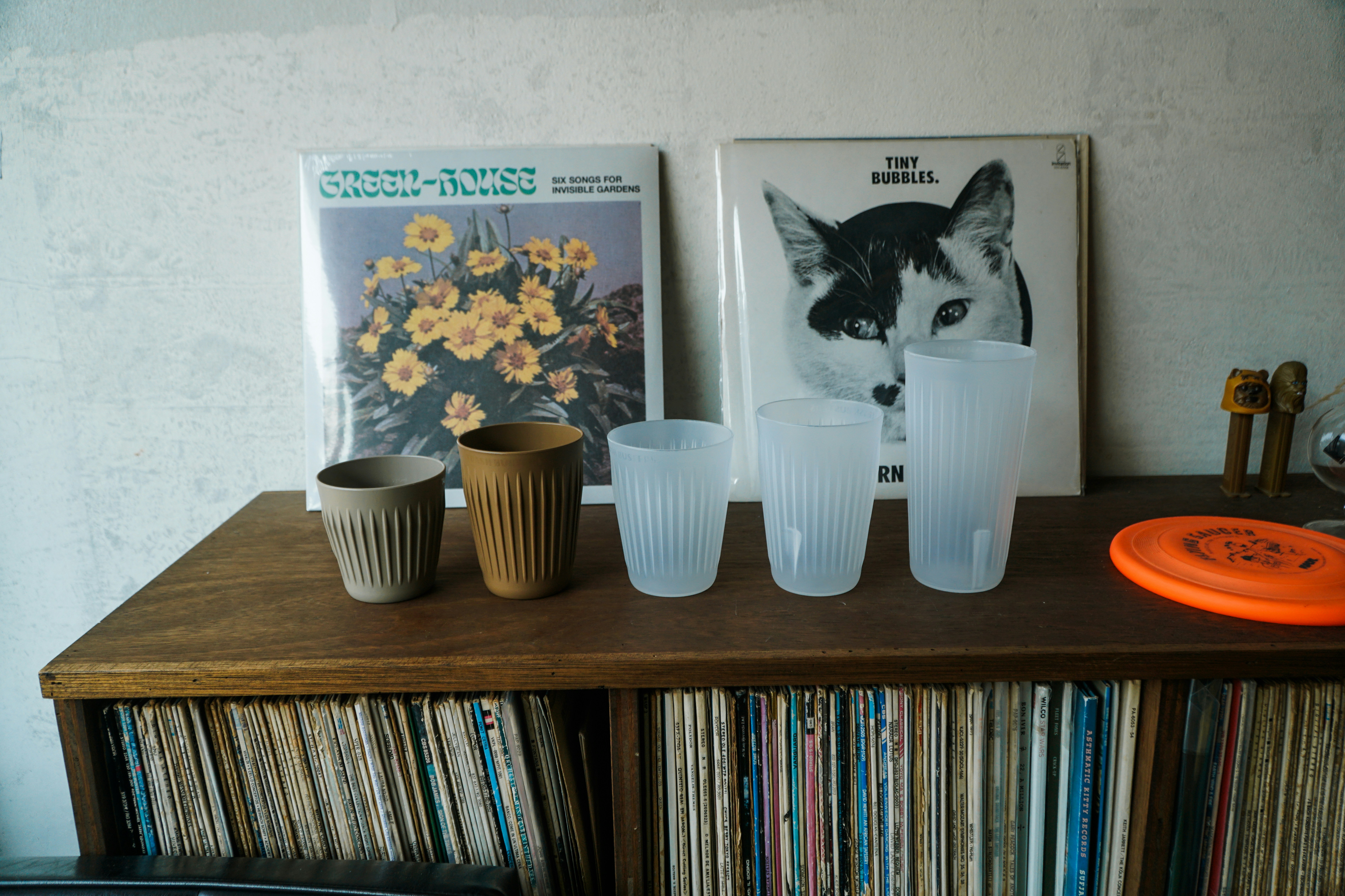 a shelf with a bunch of cups and a frisbee on it