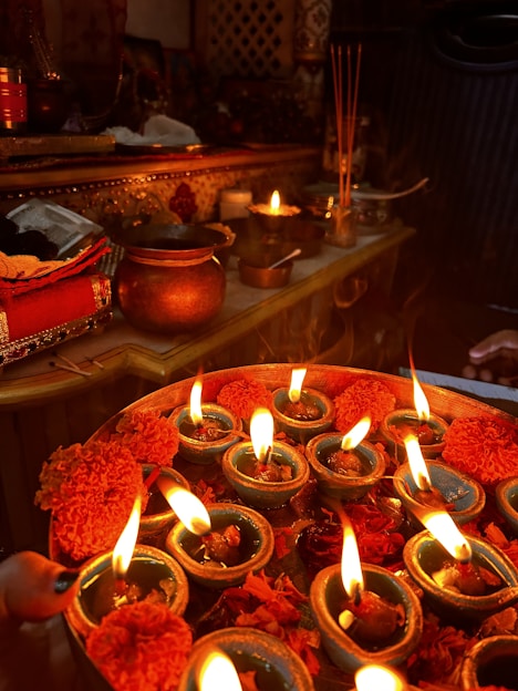 A vibrant arrangement of traditional pooja samagri items including incense sticks, diyas, and sacred powders on a wooden tray.