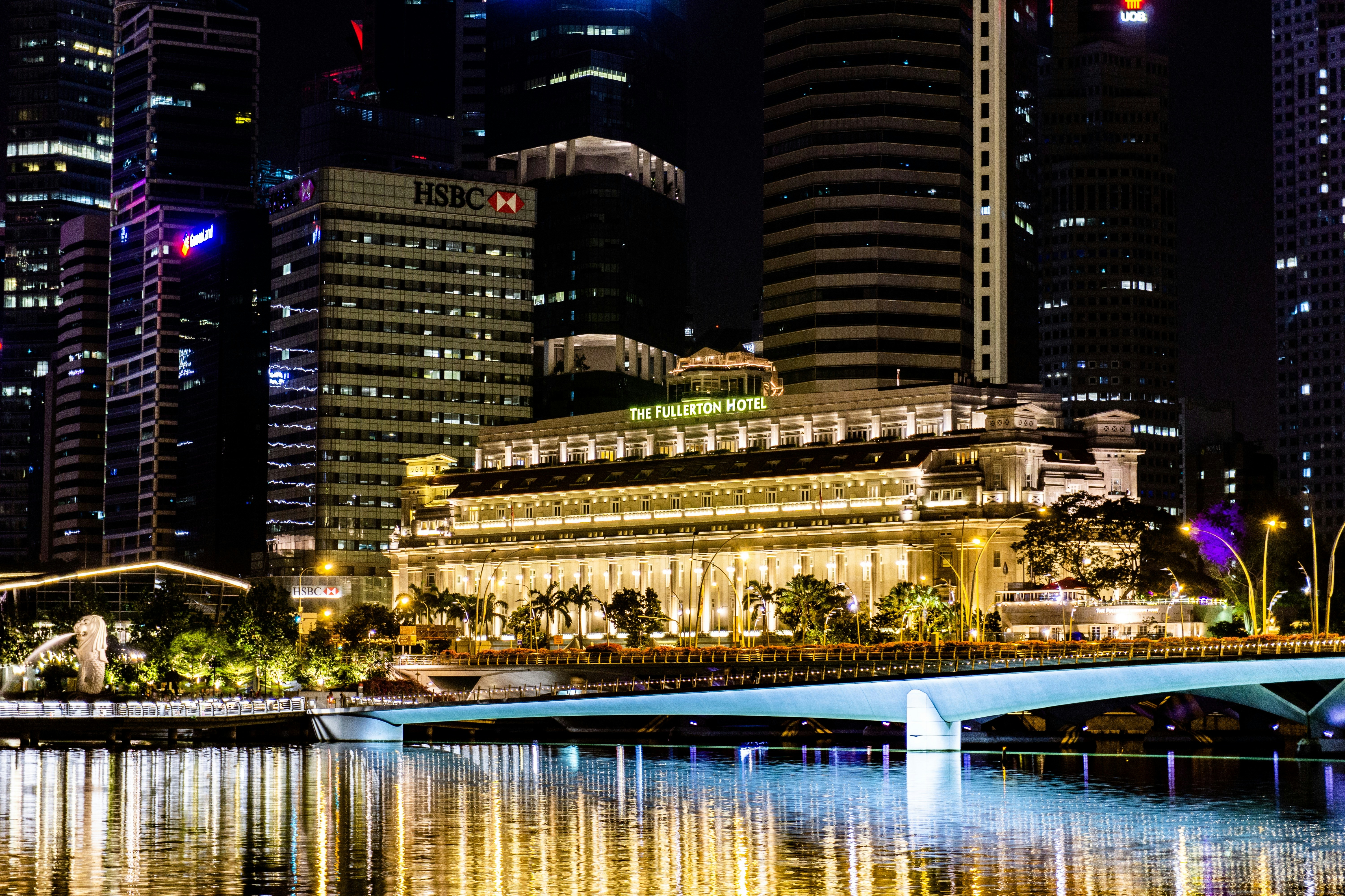 a bridge over a body of water in front of tall buildings, Fullerton Hotel