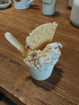 Close-up of colorful artisan ice cream scoops in waffle cones on a rustic wooden table.