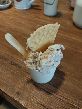 Close-up of colorful artisan ice cream scoops in waffle cones on a rustic wooden table.