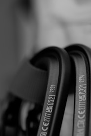 Close-up of black metallic carabiners with engraved CE and UKCA markings. The focus is on the text, providing a clear view of certification numbers and letters, set against a blurred background.
