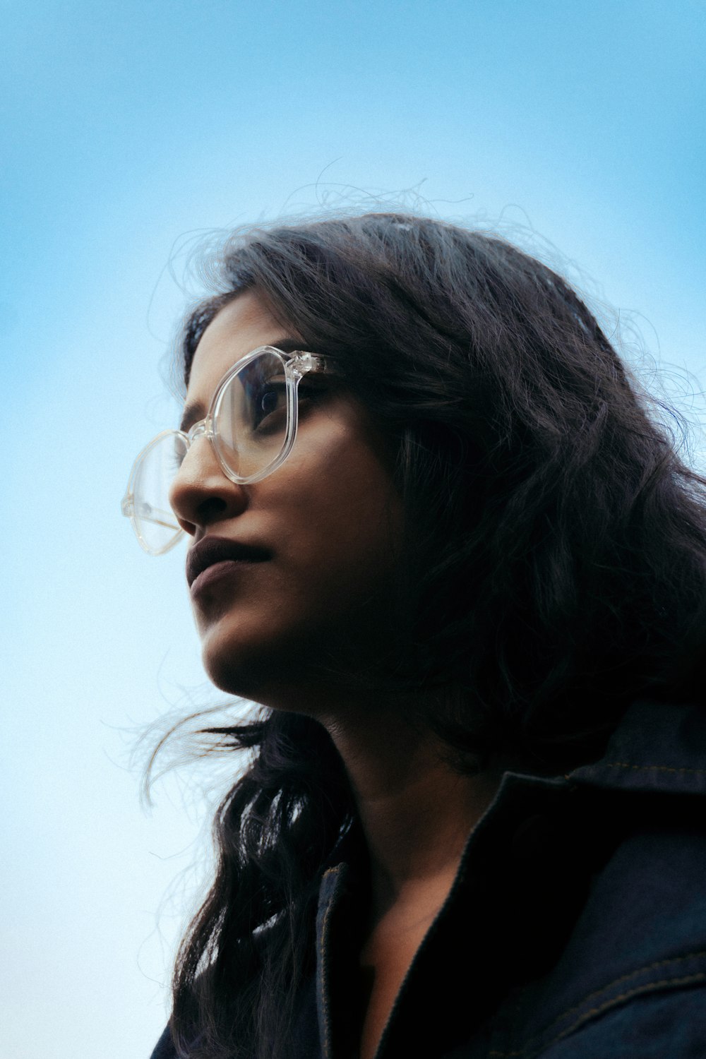 a woman wearing glasses looking up into the sky