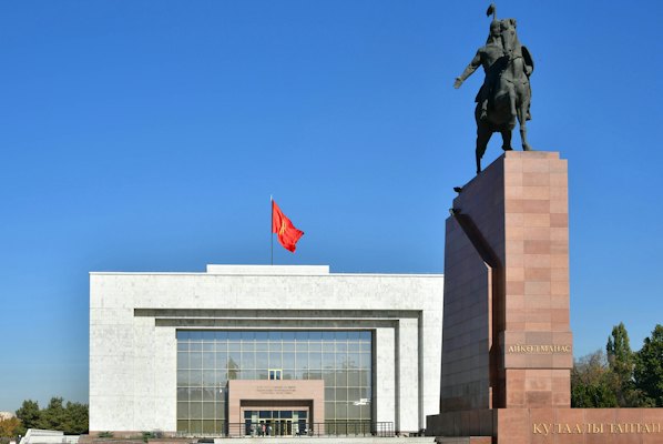 A statue of a man on a horse in front of a building — Bishkek, Kyrgyzstan