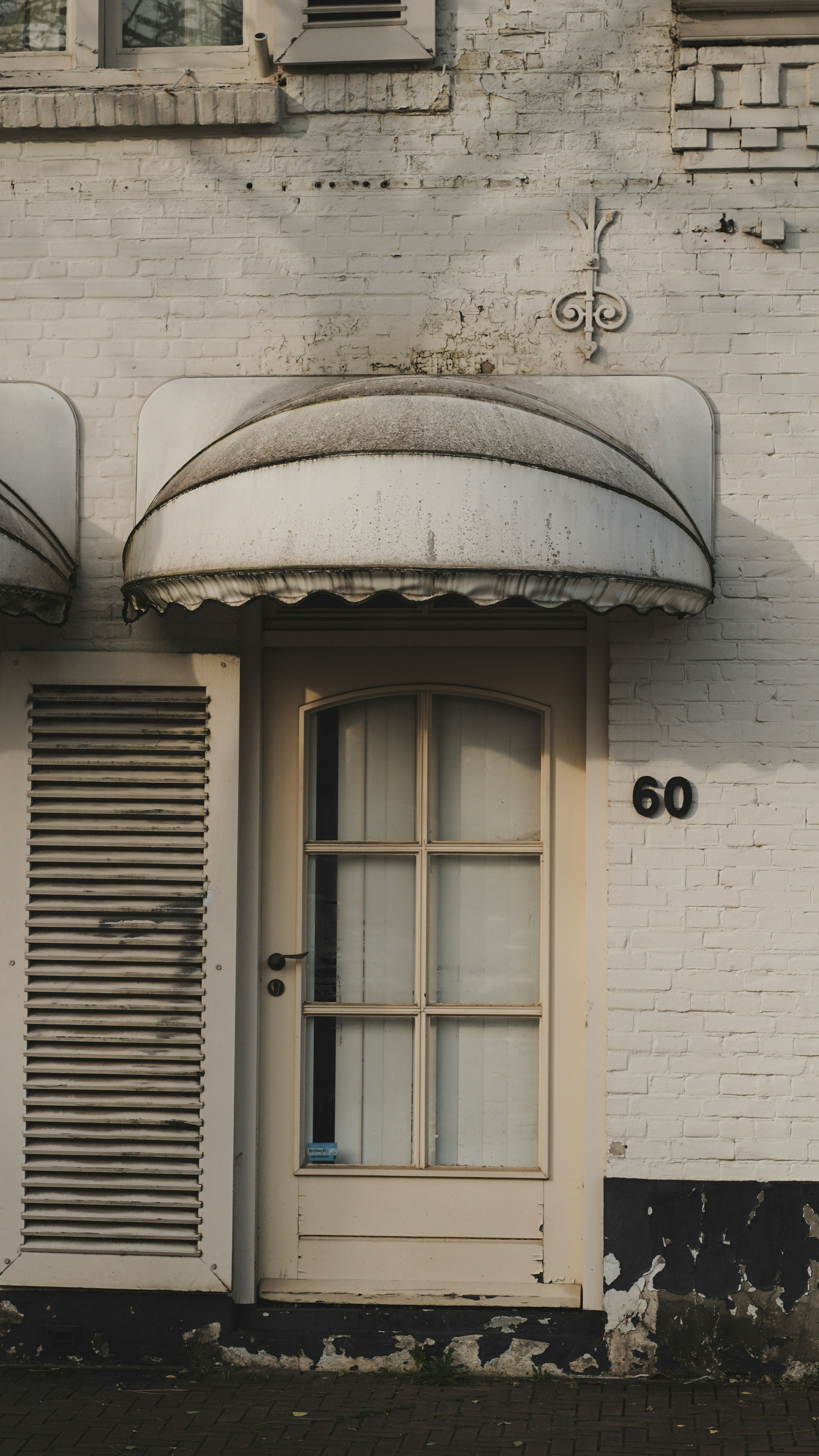 a white brick building with shutters and a door