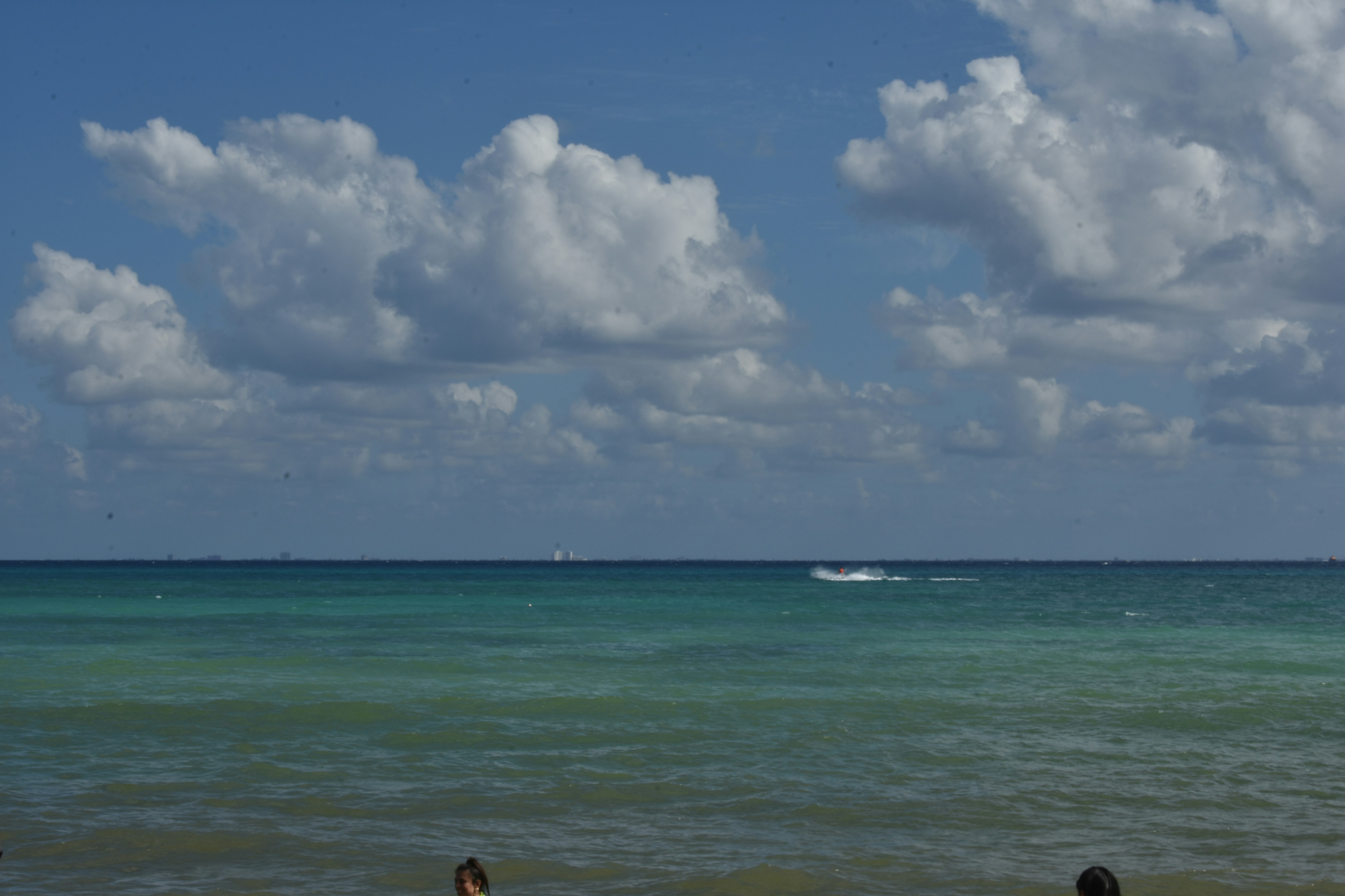 Jet ski speeding across ocean waves, water spray, bright sunny day, thrilling water sport