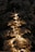 A snow-covered evergreen tree is adorned with warm, glowing lights, creating a serene and festive ambiance against a dark background.