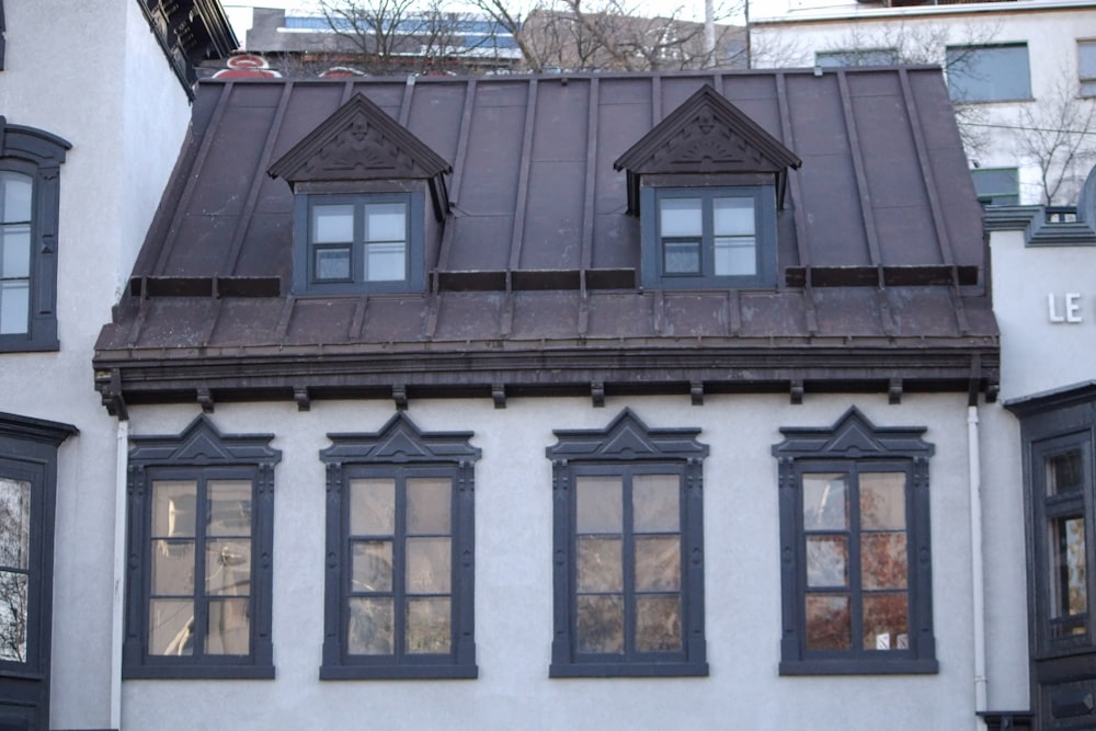 un edificio blanco con ventanas negras y techo marrón