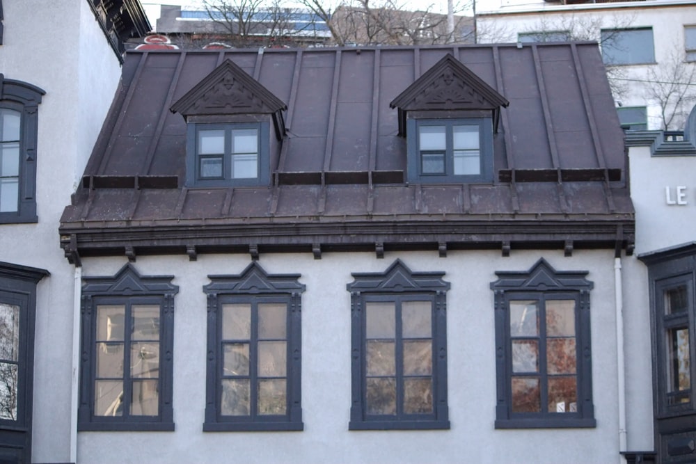 a white building with black windows and a brown roof