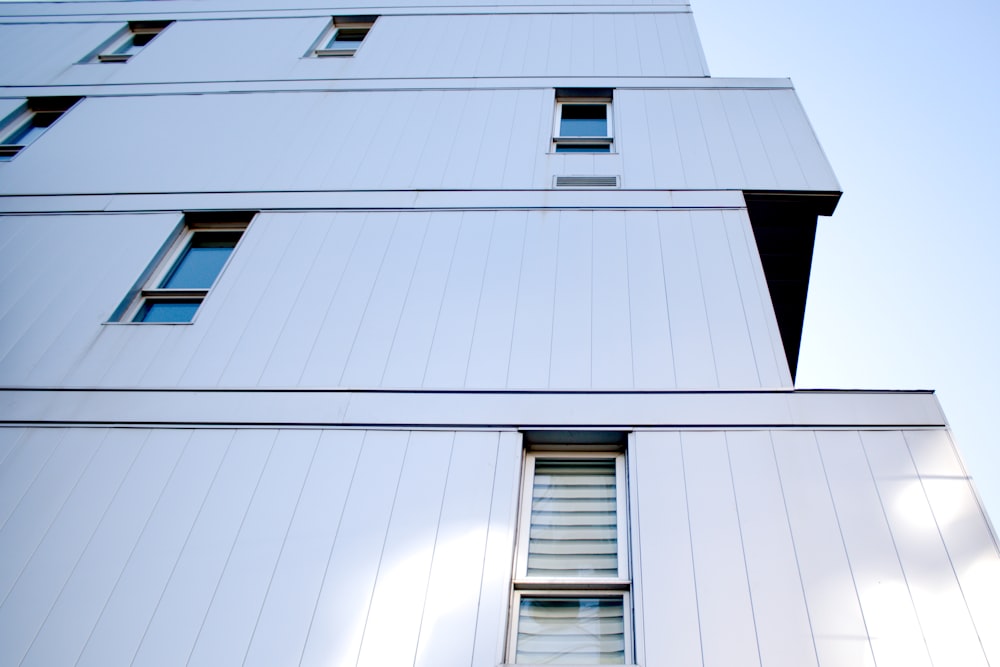 a tall white building with windows and a sky background