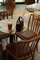 A casual canvas shoulder bag slung over a chair in a cozy cafe setting.