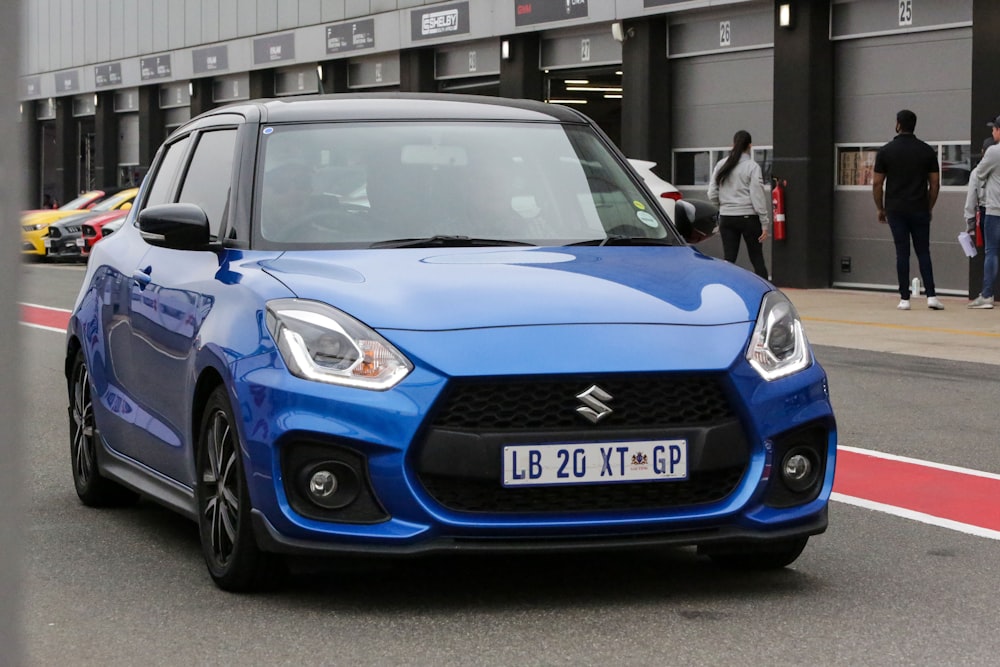 a blue suzuki car driving down a street