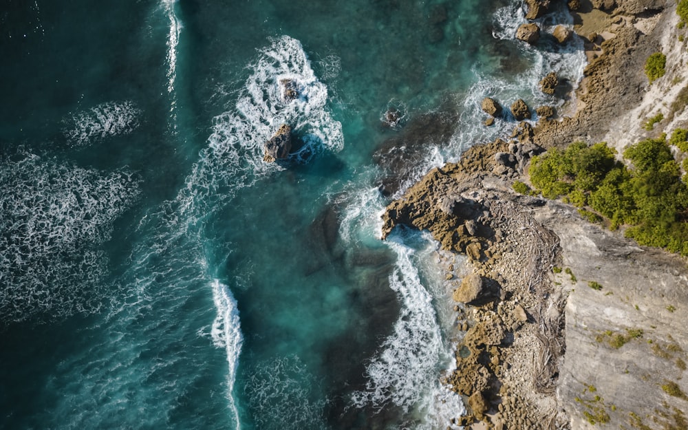 an aerial view of the ocean and rocks