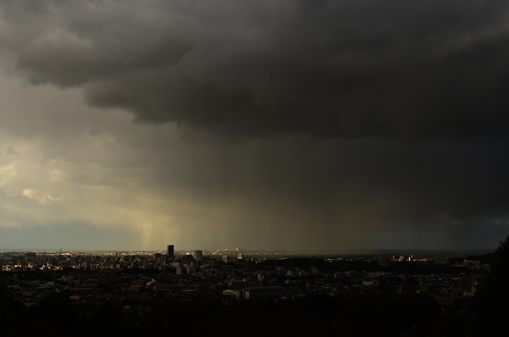 a dark cloud hovers over a city in the distance